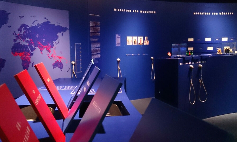Blick in die Ausstellung im Museum für Kommunikation in den blauen Ausstellungsraum - Migration von Menschen, Migration von Wörtern