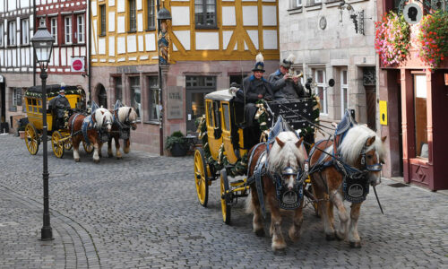 2 Postkutschen jeweils mit zwei Kutschgäulen fahren hintereinander in der Nürnberger Altstadt
