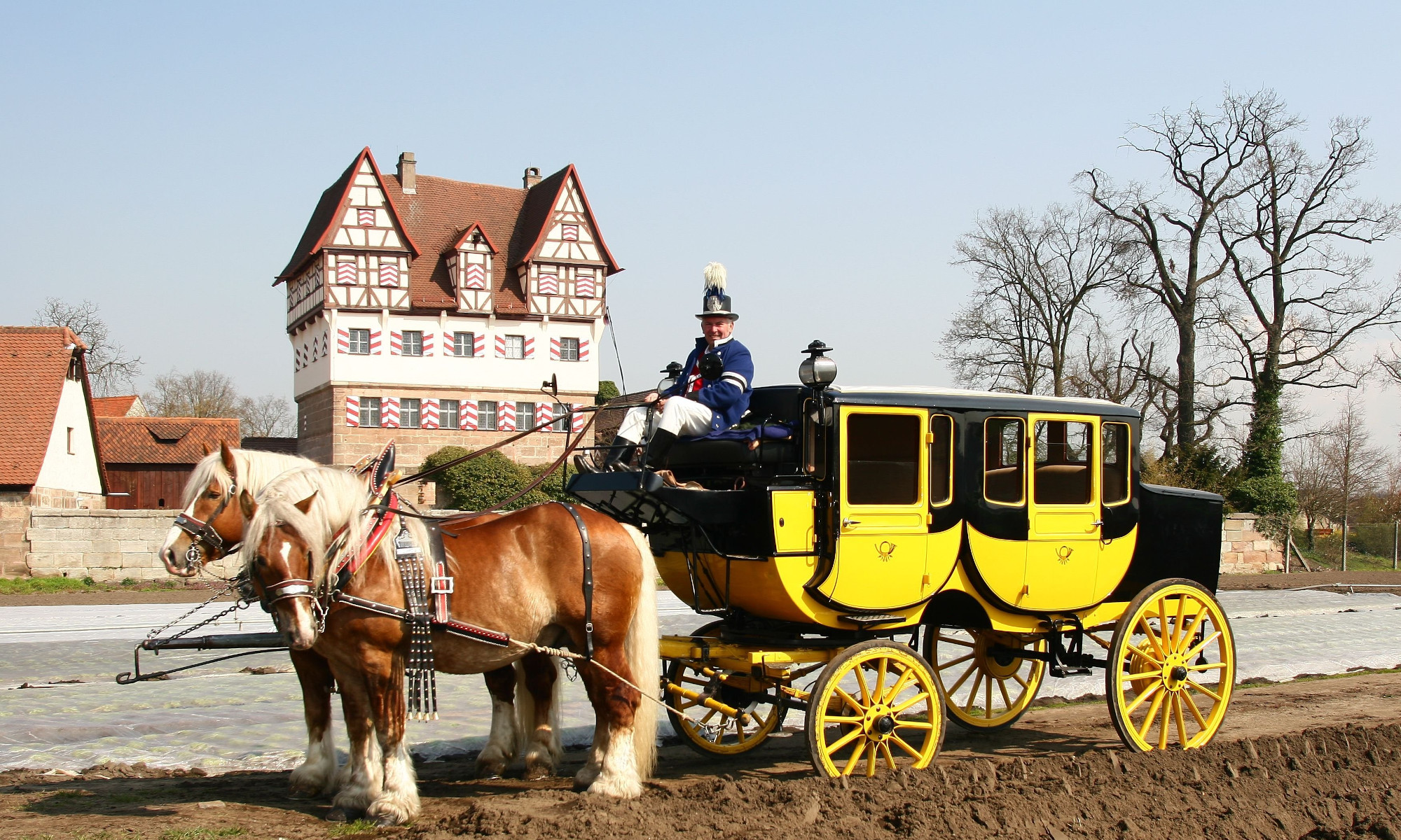 Schwarz-gelbe Postkutsche des Museum für Kommunikation mit Kutscher und 2 angespannten Kutschpferden steht vor dem Neunhofer Schloss.